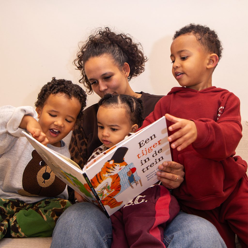 Medewerker met drie kinderen op schoot aan het lezen